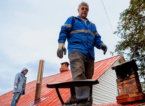 Two masons aloft reading a chimney from the roof